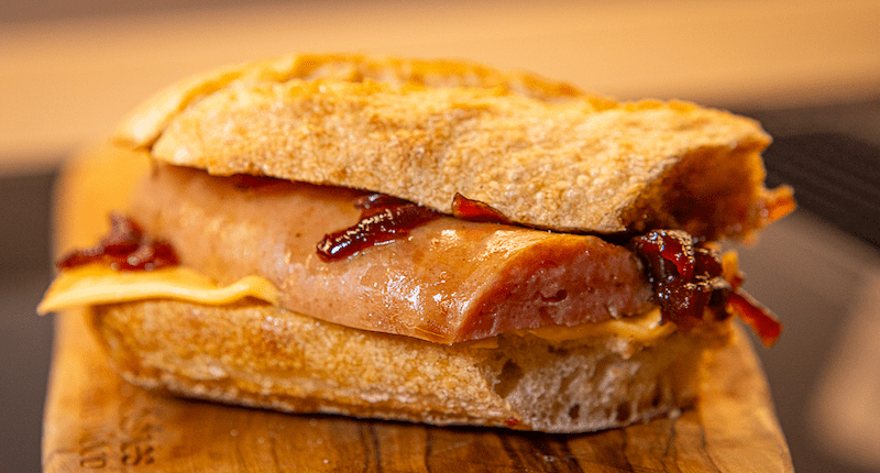 Smoked sausage bun with cheddar and caramelized onions